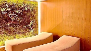 Quarto moderno com parede de madeira e uma janela ampla. Há duas áreas de estar com assentos acolchoados.