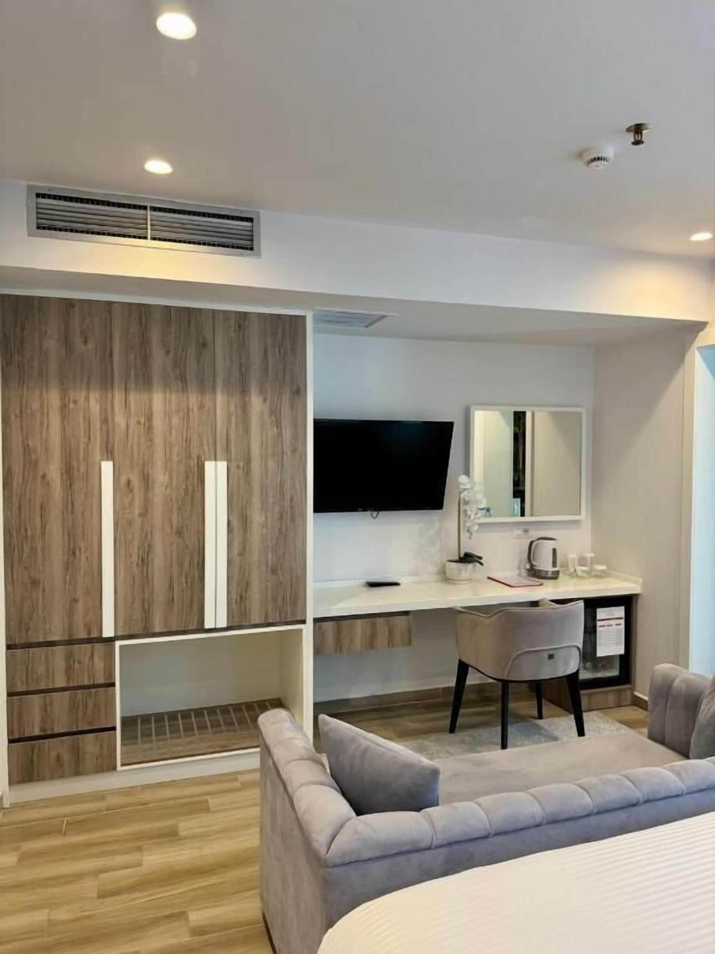 Un dormitorio moderno con una cama, un escritorio, una silla y una televisión.