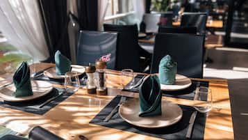 Una mesa de comedor dispuesta con platos, cubiertos y servilletas dobladas.