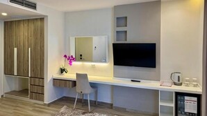 A modern room with a flat-screen TV, a desk, a chair, and a small coffee station. - Henry Resort And Spa  (Golem)