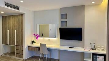 Quarto moderno com TV de tela plana, escrivaninha, cadeira e um pequeno espaço para café.
