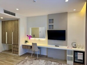 A modern room with a flat-screen TV, a desk, a chair, and a small coffee station. - Henry Resort And Spa  (Golem)
