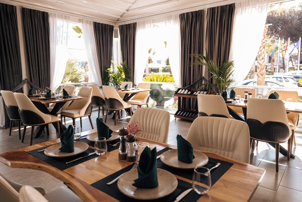 A restaurant with tables set for dining, chairs, and a wine rack.