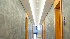 A long, narrow hallway with a glossy floor, wooden doors, and a modern ceiling with recessed lighting. - Henry Resort And Spa  (Golem)