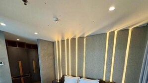 A modern hotel room with a large bed, a wardrobe, a bedside table, and a ceiling light. - Henry Resort And Spa  (Golem)