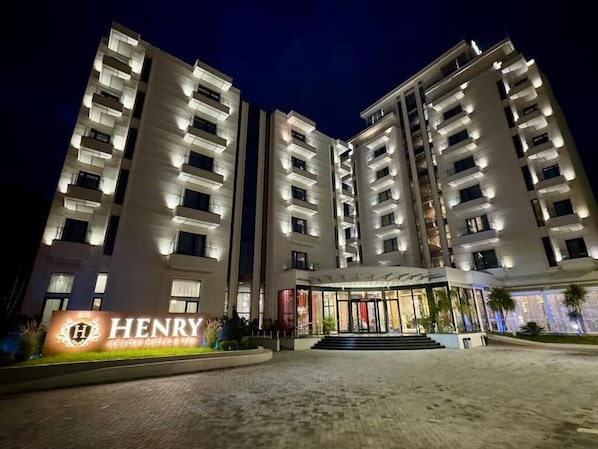 A multi-story hotel with a prominent entrance, a signboard, and a well-lit facade. - Henry Resort And Spa  (Golem)