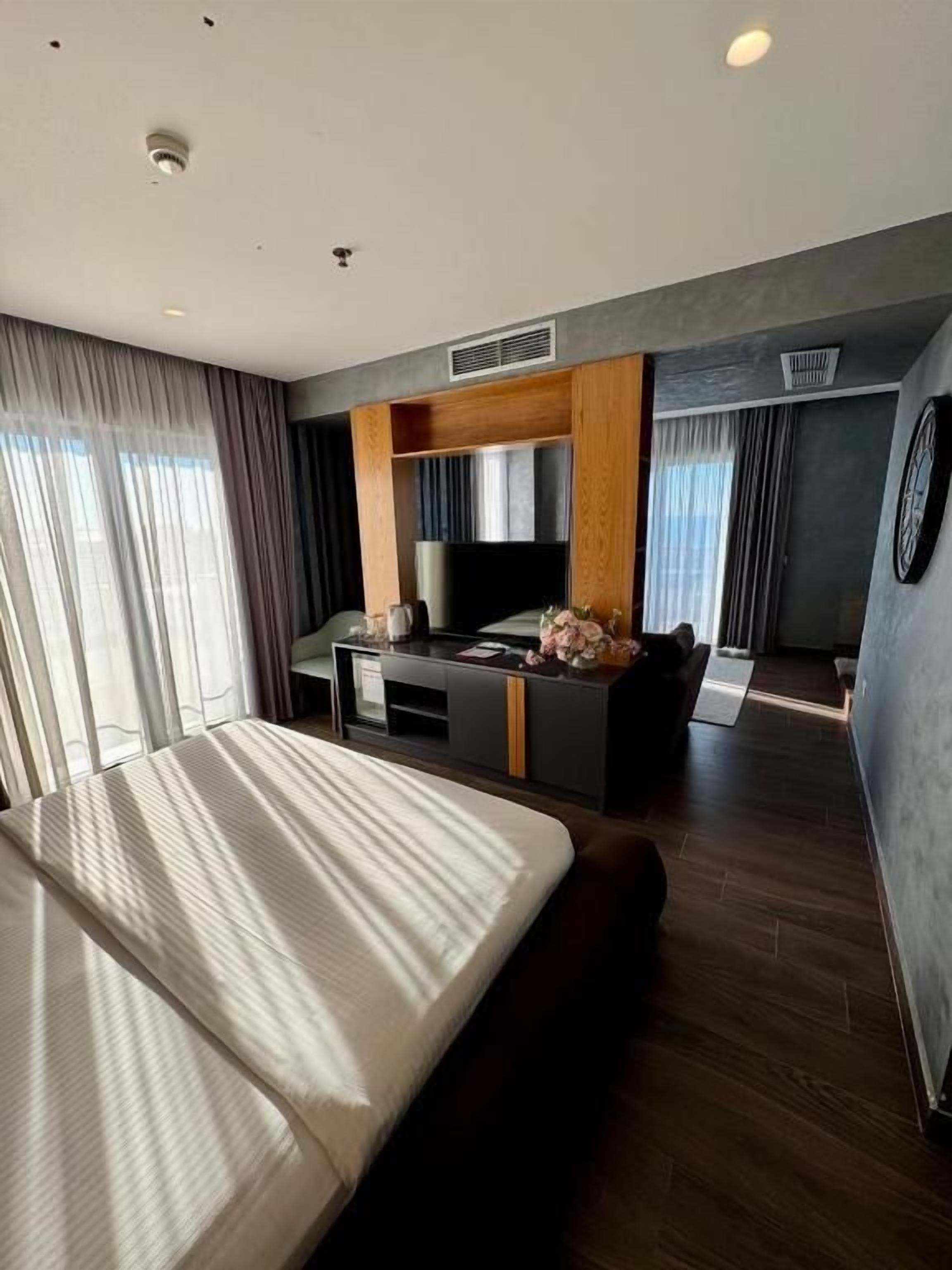 Una habitación de hotel moderna con una cama grande, un escritorio y una televisión.