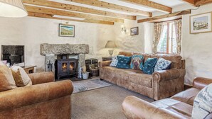 A cozy living room with a stone fireplace, leather sofas, and wooden beams on the ceiling. - A charming, detached farmhouse with plenty of character. (St Columb Major)