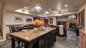 A spacious kitchen with a large island, dark cabinetry, and a fireplace.