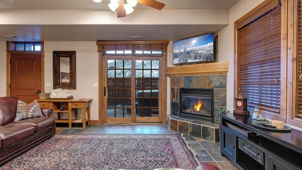 A living room with a fireplace, a television, a leather sofa, and a patterned rug.