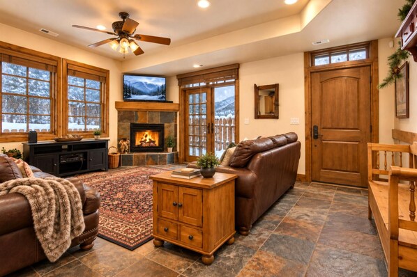 Una sala acogedora con chimenea, sofá de cuero y televisor.