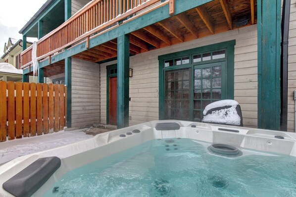 Un jacuzzi en un espacio exterior cubierto con barandas y valla de madera.