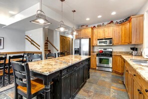 A modern kitchen with granite countertops, wooden cabinets, stainless steel appliances, and a central island with bar stools. - KBM Resorts | Walk to Lifts and Main St, Rent 1416 and 1418 Townhomes together, Pri Hot tub PPS-1418 (Park City)