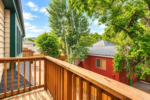 Une terrasse en bois offrant une vue sur un bâtiment rouge et les arbres environnants.