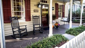 A porch with two rocking chairs, a welcome sign, and a house number 332.