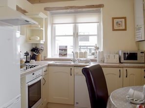 A kitchen with a stove, oven, sink, and a microwave.