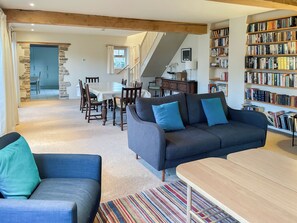 A living room with a sofa, chairs, a dining table, and a staircase leading to another room. - 3 bedroom accommodation in Helmsley (Helmsley)