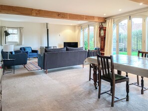 A living room with a sofa, a dining table with chairs, a lamp, and a large window. - 3 bedroom accommodation in Helmsley (Helmsley)
