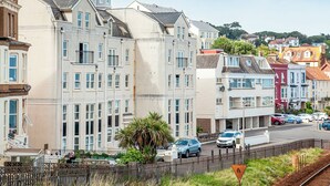 Une rangée de maisons de ville, avec une rue devant, une clôture et une voie ferrée.