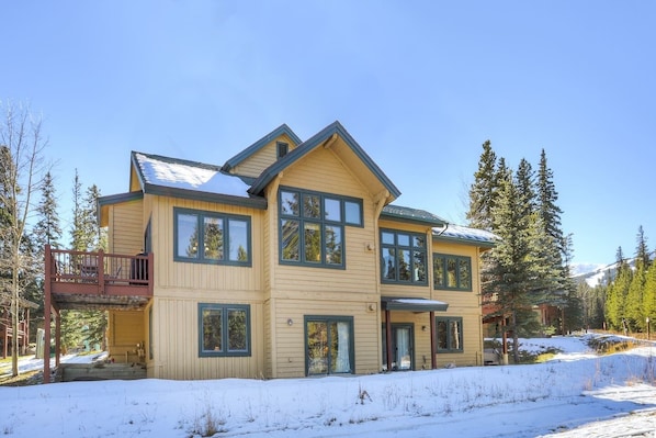 A two-story house with a large porch, multiple windows, and a snow-covered landscape.