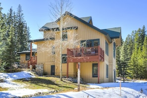 A two-story building with a balcony, surrounded by trees and snow.