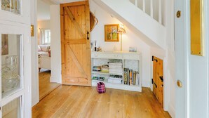 A staircase with white railings, a wooden door, a white console table with books, and a pink bag on the floor. - Beautiful house, peaceful surrounding yet close to towns and beaches. (Faversham)