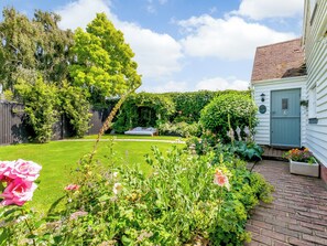 A well-maintained garden with a lawn, flowering plants, and a wooden bench.