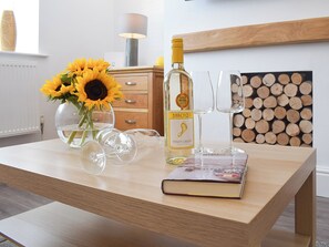 A wooden table with a bottle of Barefoot Pinot Grigio, two wine glasses, a book, and a vase with sunflowers. - 3 bedroom accommodation in Amble, near Warkworth (Amble, near Warkworth)