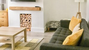 Ein Wohnzimmer mit Fernseher, Kamin, Sofa und einem gerahmten Bild an der Wand.