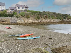 Una playa rocosa con kayaks y un muro de piedra.
