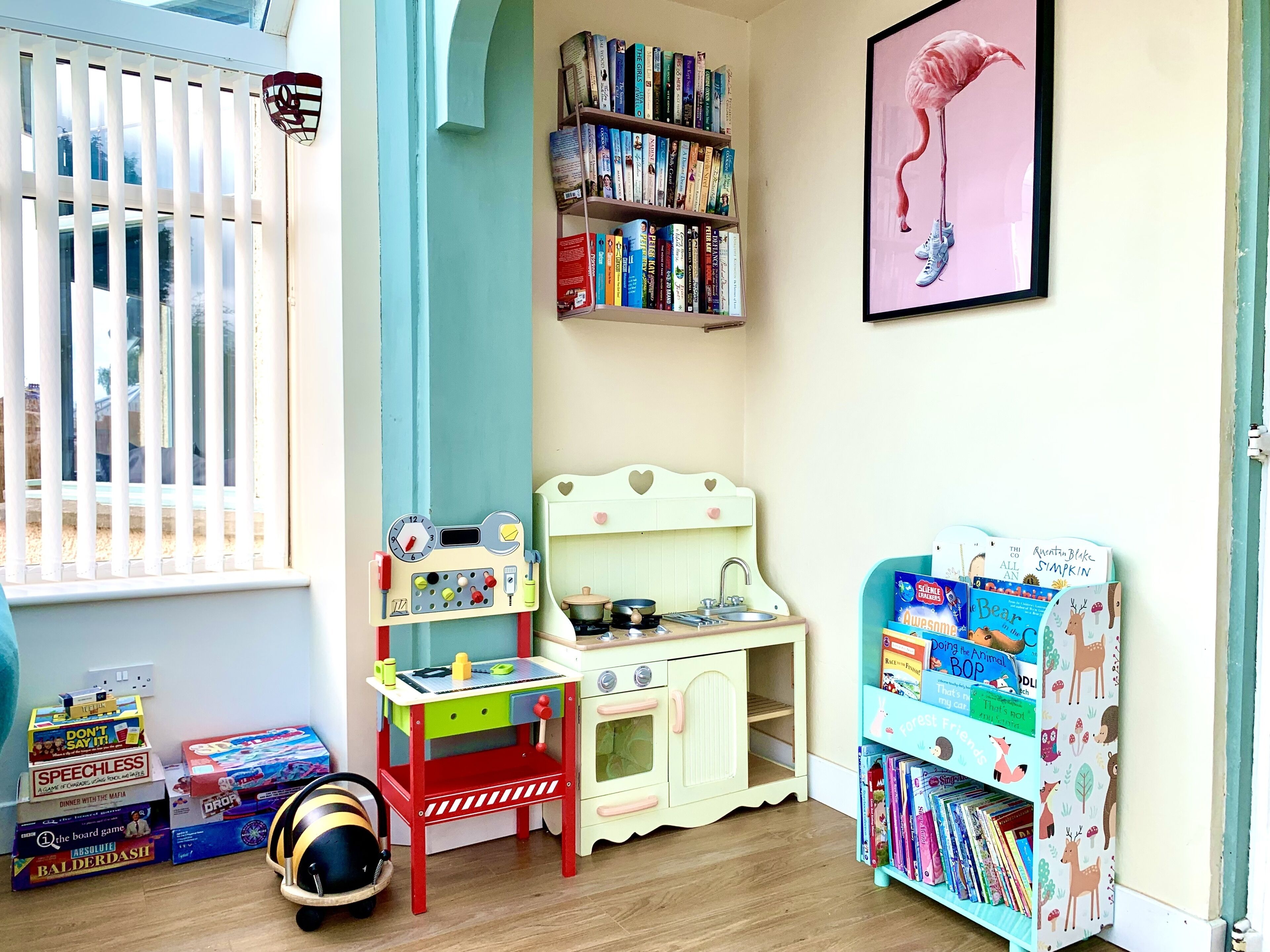 Um quarto de criança com estante de livros, cozinha de brinquedo e um conjunto de trem.