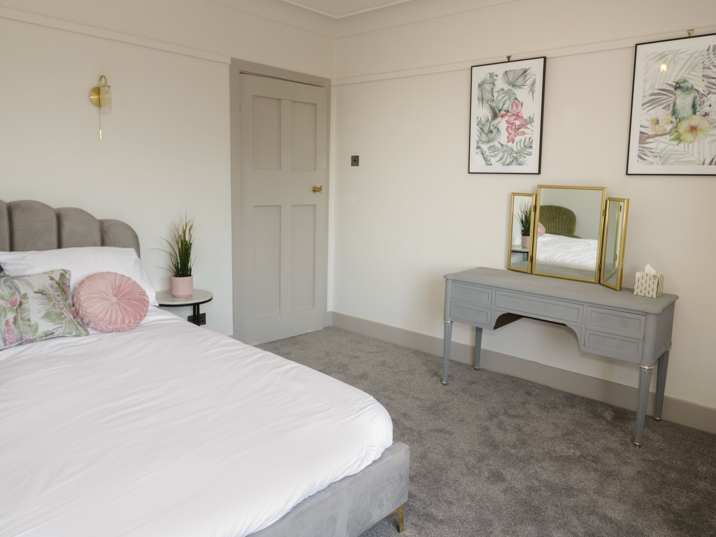 A bedroom with a bed, bedside table, dresser, and a door.