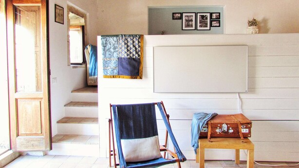 A room with a wooden ceiling, a blue and white patterned wall hanging, a wooden chest of drawers, and a blue chair. - SR-G267-LENZ21A1 - Dimora Il Balcone Barocco (Palazzolo Acreide)