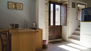A kitchen with a wooden counter, stone wall, and a door leading to a balcony. - SR-G267-LENZ21A1 - Dimora Il Balcone Barocco (Palazzolo Acreide)