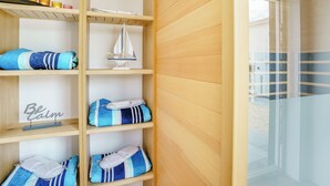 A wooden shelving unit with folded towels, a sailboat decoration, and a 'Be Calm' sign.