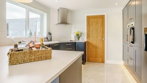 A modern kitchen with a large island, a wooden door, and a built-in oven.