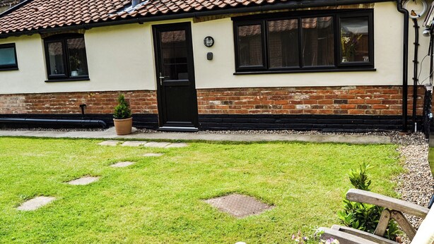 A patio with a table set for a meal, a brick house in the background, and a small garden area. - 1 bedroom accommodation in Great Hockham, near Thetford (Great Hockham, near Thetford)