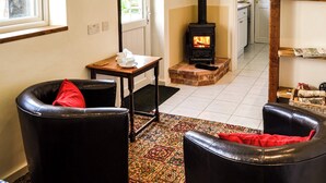 A cozy room with a fireplace, a small table with cups, and two leather chairs. - 1 bedroom accommodation in Great Hockham, near Thetford (Great Hockham, near Thetford)