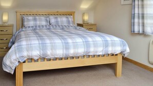 Un dormitorio con cama de madera, una mesita de noche, una lámpara y una ventana con cortinas.