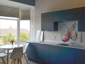 A modern kitchen with a dining area, a large window, and a view of the outside.