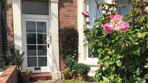 A traditional building with a white door, brick facade, and a window with a white frame. - Percy Park Apartment (TYNEMOUTH)