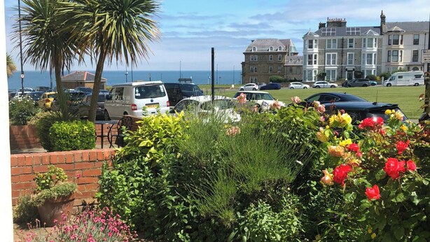 A coastal hotel with a parking area, a palm tree, and a view of the sea. - Percy Park Apartment (TYNEMOUTH)