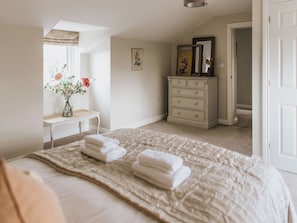 Une chambre à coucher avec un lit, une commode, une coiffeuse et un miroir.