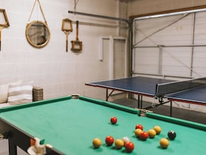 Une table de billard avec des billes, une table de ping-pong et un miroir au mur.
