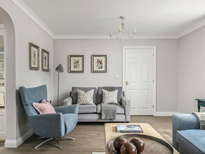 Ein Wohnzimmer mit blauem Sessel, grauem Sofa und einem Couchtisch mit Dekoration.