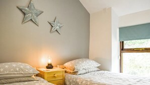 A bedroom with two beds, star-patterned bedding, a bedside table with a lamp, and star-shaped wall decorations. - 2 bedroom accommodation in Dolwyddelan (Dolwyddelan)