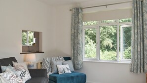 A cozy living room with a sofa, a small table, and a window with curtains. - 2 bedroom accommodation in Wool, near West Lulworth (Wool, near West Lulworth)