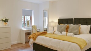 Une chambre à coucher avec un grand lit, une table de chevet, un miroir et une commode.