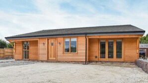 Une cabane en bois avec un toit en pente, de grandes fenêtres et une allée gravillonnée.