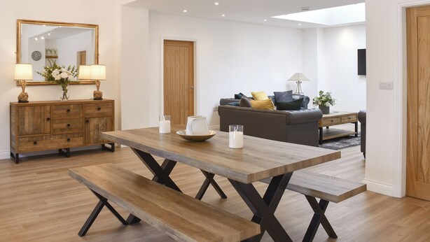 Un vaste espace de vie comprenant une table à manger en bois, un canapé et un grand miroir.